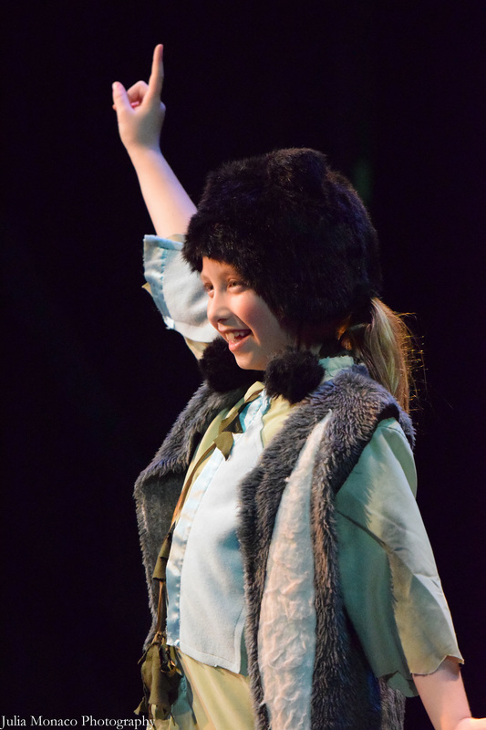 A young girl smiles and points in the air, as she plays the role of one of Peter Pan's friends, in the musical 